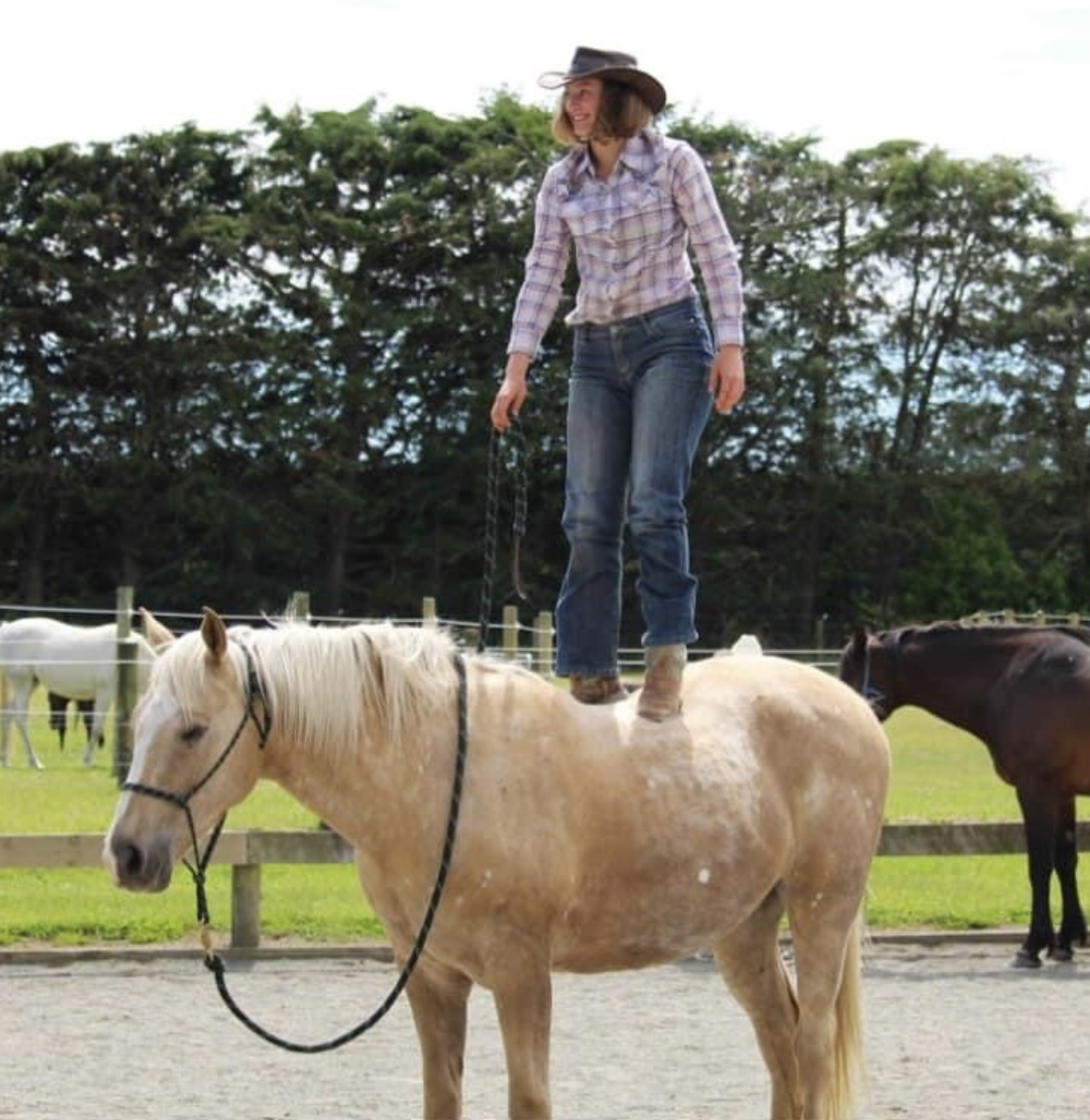 Nia Isabella standing on a palomino horse—trust and partnership